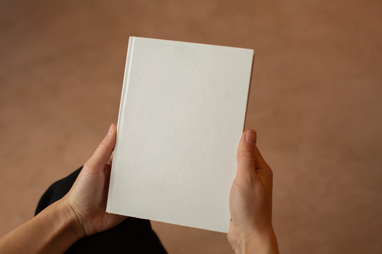 A person holding a blank hardcover book. Perfect for mockup and design templates.